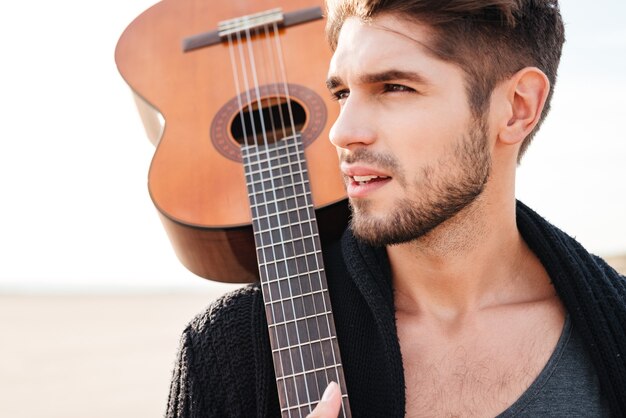 Bliska Portret Młodego Mężczyzny Dorywczo Z Gitarą Na Ramieniu Na Plaży
