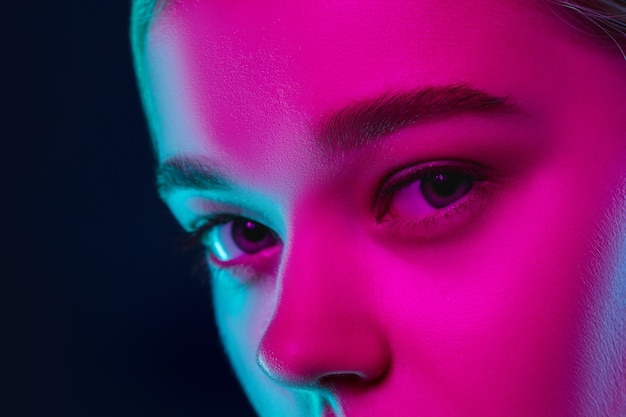 Bliska portret modelki w świetle neonowym na ciemnym tle studio