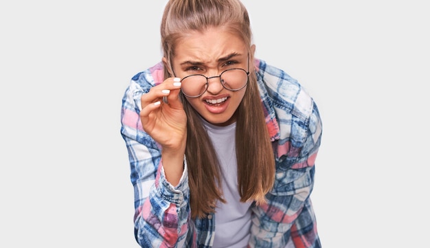 Zdjęcie bliska portret niezadowolonej i przesłuchiwanej młodej kobiety, która zdejmuje przezroczyste okulary, patrząc poważnie na omawianie ważnych rzeczy, ubrana w strój casual pozowanie na białym tle