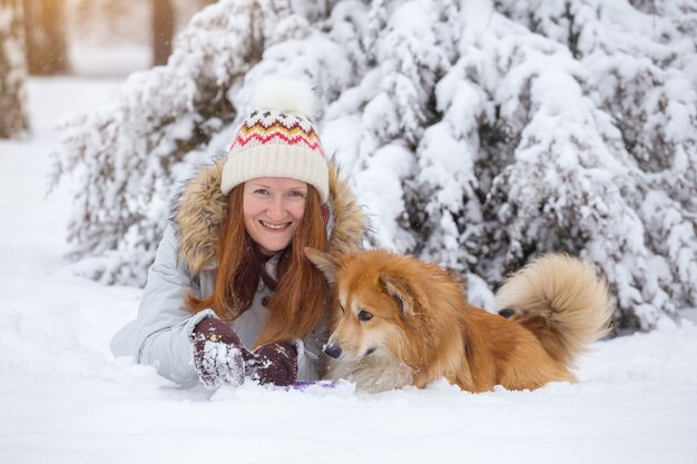 Bliska portret psa corgi puszysty i jego właściciel bawiący się na zimowy spacer na świeżym powietrzu