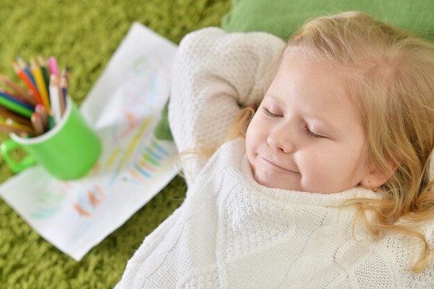 Bliska portret ślicznej małej dziewczynki leżącej na poduszce na podłodze w domu