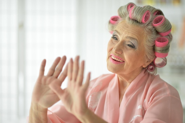 Bliska portret starszej kobiety w szlafroku suszenie lakieru do paznokci