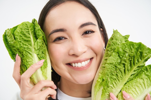 Bliska portret szczęśliwej koreańskiej kobiety pokazuje jej twarz z sałatą jedzącą kapustę lubi warzywa