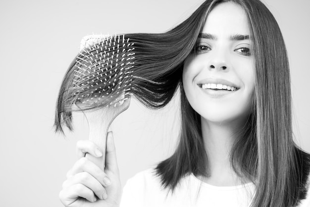 Zdjęcie bliska portret szczęśliwej pięknej dziewczyny z lśniącymi włosami z grzebieniem atrakcyjna uśmiechnięta kobieta brushin