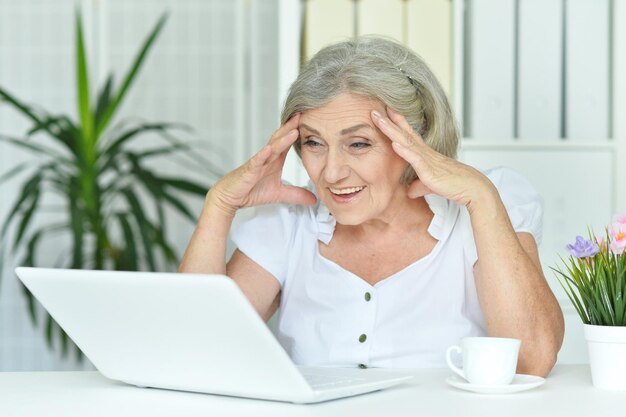 Bliska portret szczęśliwej starszej kobiety za pomocą laptopa