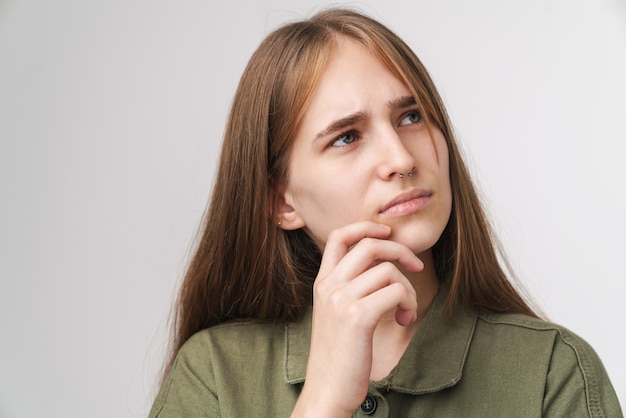 Bliska portret zamyślonej ładnej młodej dziewczyny z długimi blond włosami stojącymi