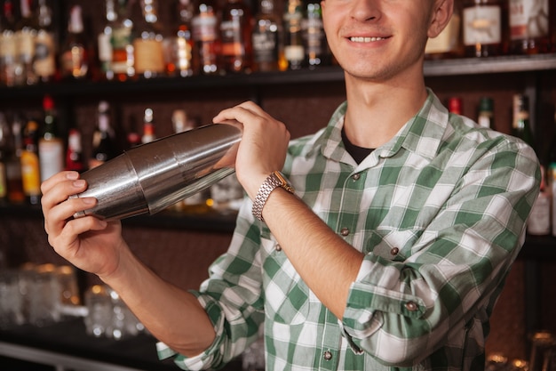 Bliska przycięty strzał nierozpoznawalny męski barman przygotowuje napój dla klienta, używając shaker cyny