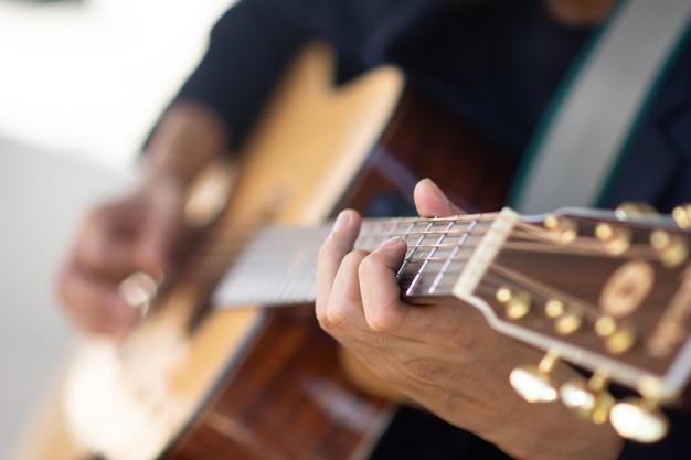 Bliska ręka grająca na gitarze akustycznej złapać akordy gitarowe
