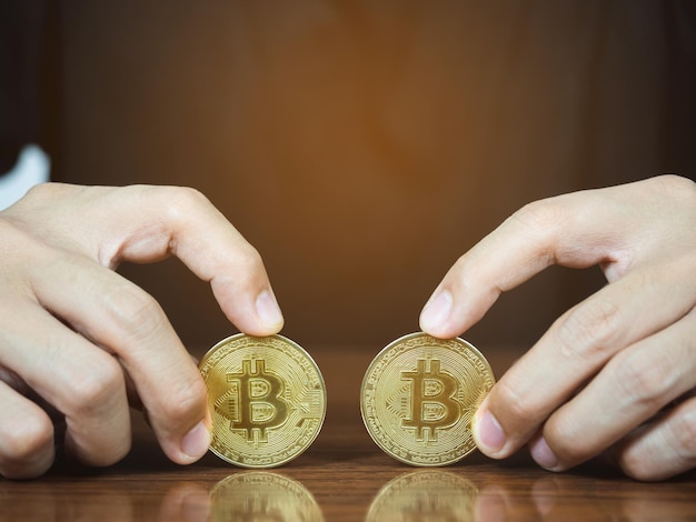 Bliska ręka mężczyzny pokazująca złoty bitcoin na stole