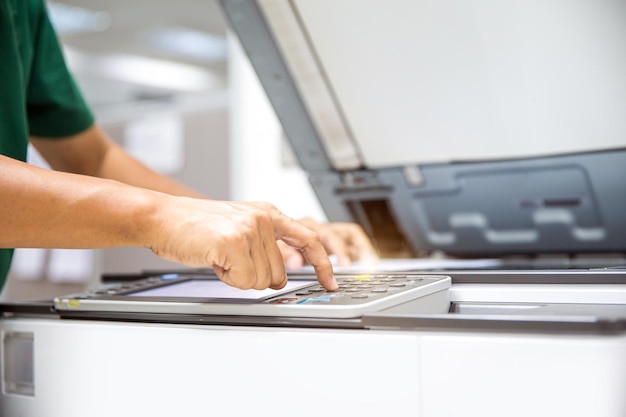 Zdjęcie bliska ręka pracownika biurowego naciśnij przycisk kopiowania na panelu, aby użyć kserokopiarki