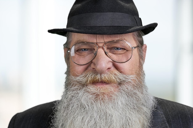 Bliska starszy brodaty mężczyzna patrząc na kamery z uśmiechem. Portret wesoły dziadek na niewyraźne tło.