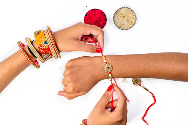 Zdjęcie bliska widok z góry siostrzane ręce trzymające rakhi dla raksha bandhan na białym tle