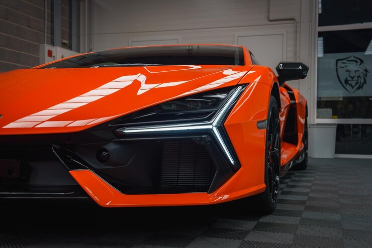 Bliskie zdjęcia pomarańczowego Lamborghini Revuelto na karmicznej podłodze w pomieszczeniach