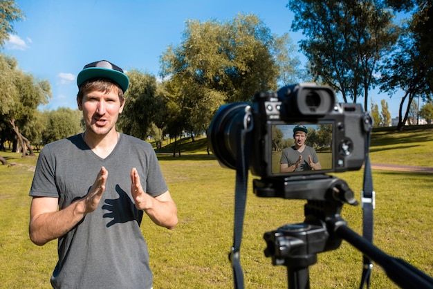 Bloger nagrywa wideo kamerą na zewnątrz w słoneczny dzień