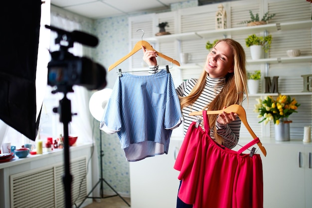 Blogerka mody w dżinsach i turtleneck pokazująca przyzwoite kolorowe koszule na kamerze Stylistka wpływowa dziewczyna pokazująca modne ubrania nagrywająca odcinek vlog dla swojego kanału Lider opinii wyznacza trendy