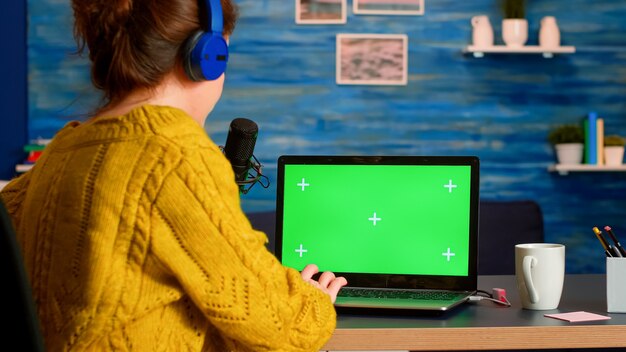 Blogger pisze na laptopie z zielonym ekranem, nagrywając nową serię podcastów dla odbiorców