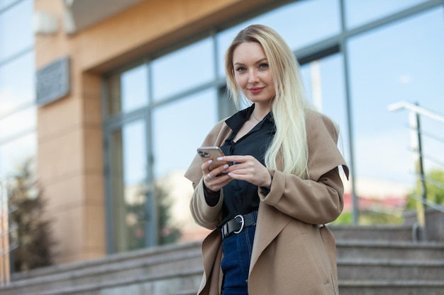 Blond biznesowa dama używa smartfona na zewnątrz