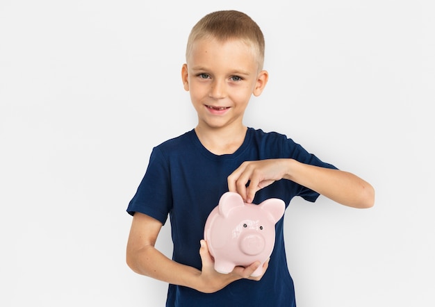 Blond chłopiec ratuje jego pieniądze w prosiątko banku