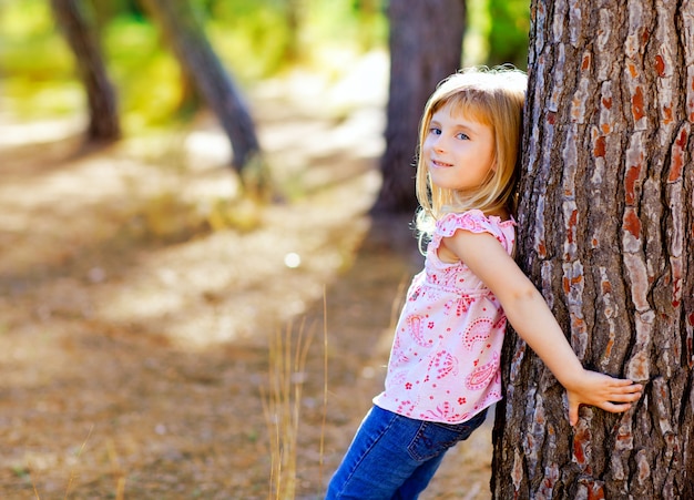 blond dziecko dziewczynka na pniu drzewa jesienią