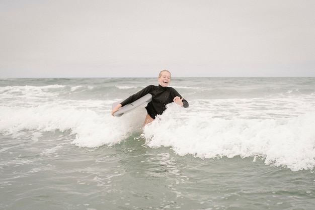 Blond dziewczyna bodyboarding w oceanie