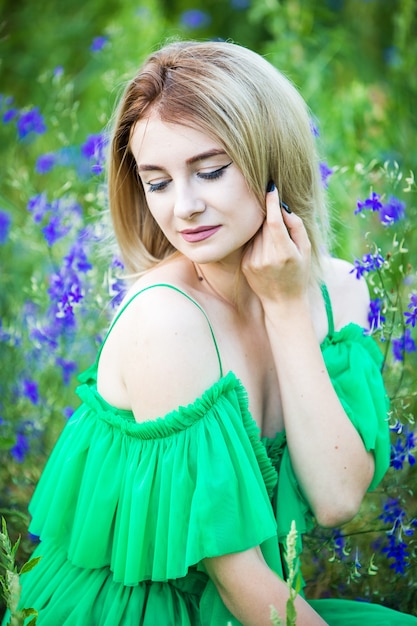 Blond dziewczyna europejska w zielonej sukni na charakter z niebieskimi kwiatami