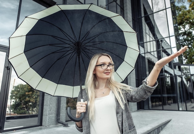 Blond kobieta trzymająca parasolkę i sprawdzająca deszcz