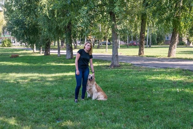 Zdjęcie blond kobieta ze swoim psem retrieverem w letnim parku
