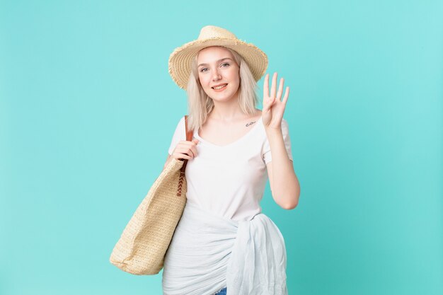 blond ładna kobieta uśmiecha się i wygląda przyjaźnie, pokazując numer cztery. koncepcja lato