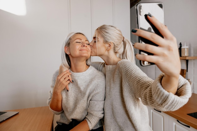 Blond młoda szczęśliwa matka i córka w kuchni robią selfie dla sieci społecznościowej blogowanie blog rodzinny