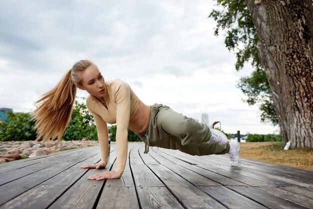 Blond młoda wysportowana kobieta ćwiczy w parku w środowisku miejskim Atrakcyjna kobieta lekkoatletycznego ćwiczenia na świeżym powietrzu rano kopia przestrzeń Koncepcja fitness fitness