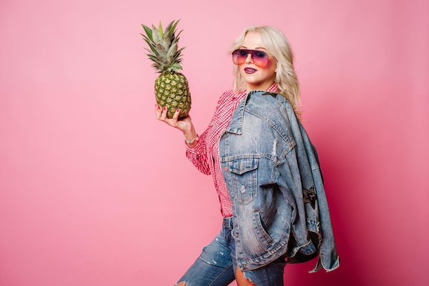 Blond szczęśliwa kobieta z ananasem pozuje na kolorowym tle