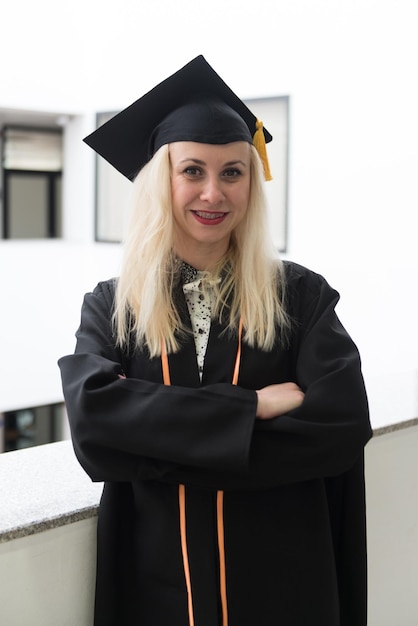 Zdjęcie blondynka absolwentka college'u lub liceum z pewnością nosząca czarną czapkę i suknię na uroczystości