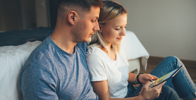 Blondynka I Jej Kochanek Siedzą Na Podłodze I Patrząc Na Ekran Tabletu