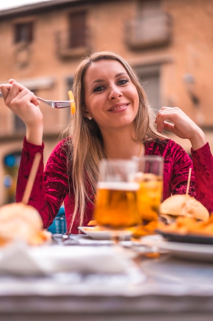 Blondynka jedząca obiad w czerwonej sukience obok średniowiecznego zamku