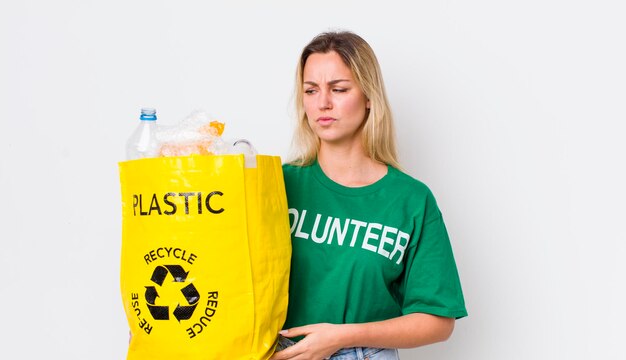 Blondynka ładna kobieta czuje się smutna, zdenerwowana lub zła i patrzy na bok koncepcji recyklingu