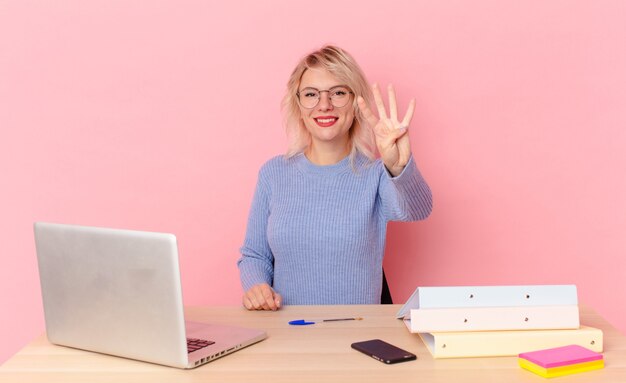 blondynka ładna kobieta młoda ładna kobieta uśmiechnięta i patrząc przyjazna, pokazując numer cztery. koncepcja biurka w miejscu pracy