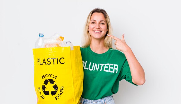 Blondynka ładna kobieta uśmiecha się pewnie wskazując na własną koncepcję recyklingu szerokiego uśmiechu