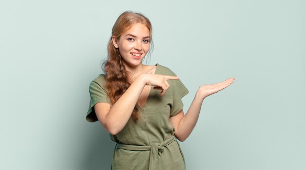 Blondynka ładna kobieta uśmiecha się radośnie i wskazuje na kopiowanie miejsca na dłoni z boku, pokazując lub reklamując obiekt