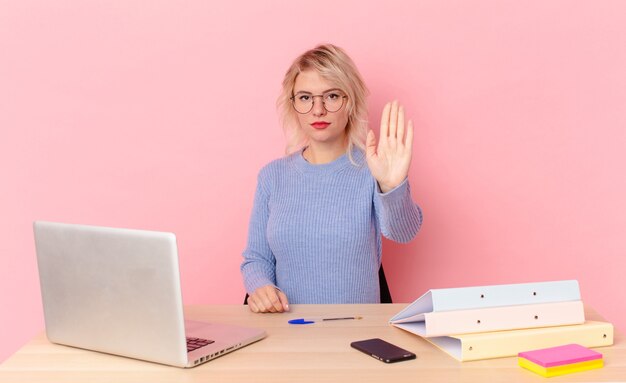 Blondynka ładna Młoda ładna Kobieta Szuka Poważnego Wyświetlono Otwartej Dłoni Co Gest Stop. Koncepcja Biurka W Miejscu Pracy