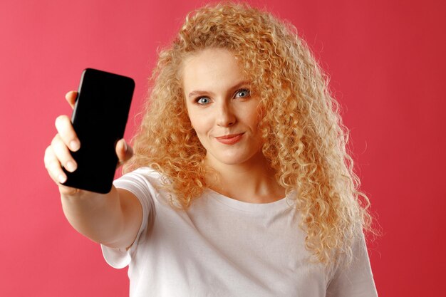 Blondynka młoda kobieta pokazuje czarny ekran smartfona z miejscem na kopię