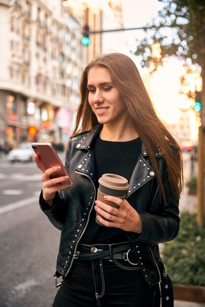 Zdjęcie blondynka patrząc na telefon z kawą