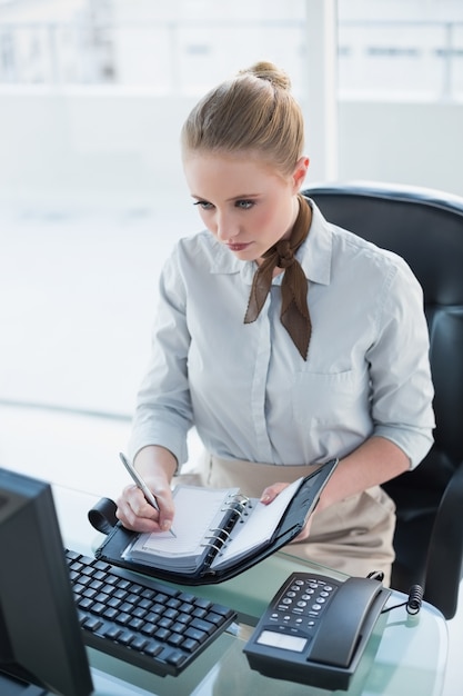 Blondynka poważny bizneswomanu writing w dzienniczku