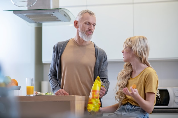 Blondynka siedzi w kuchni i rozmawia z tatą