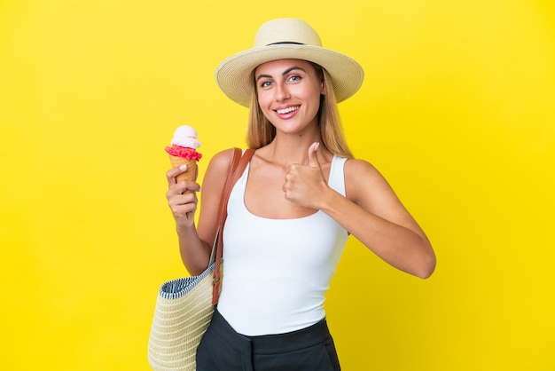 Blondynka Urugwajska latem trzymająca lody na żółtym tle dająca gest kciuka w górę