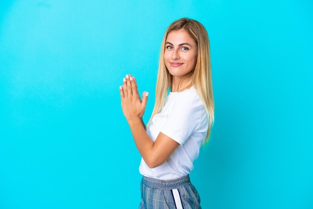 Blondynka urugwajska na białym tle na niebieskim tle knuje coś