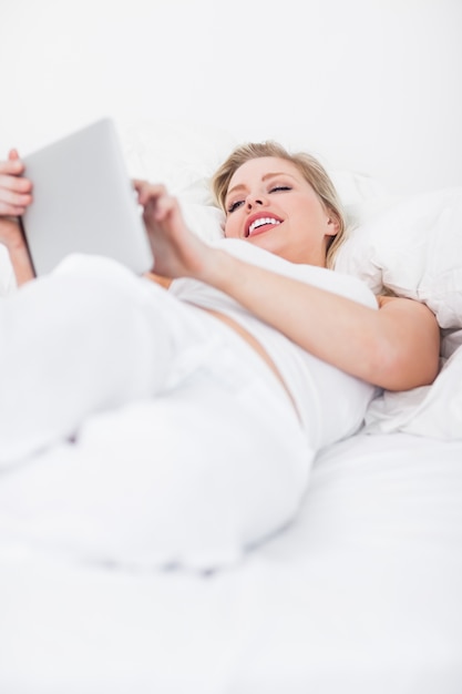 Blondynka uśmiecha się podczas korzystania z czytnika ebook