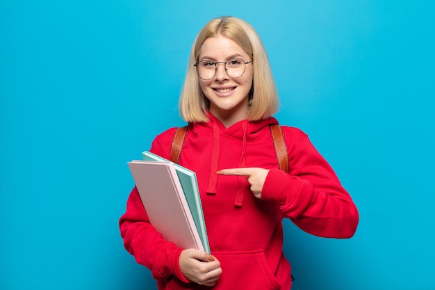 Blondynka uśmiecha się radośnie, czuje się szczęśliwa i wskazuje na bok i do góry, pokazując obiekt w przestrzeni kopii