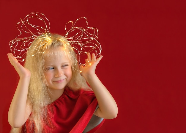 Zdjęcie blondynka uśmiechnięta dziewczyna z kokardą wykonane z drutu lampki choinkowe