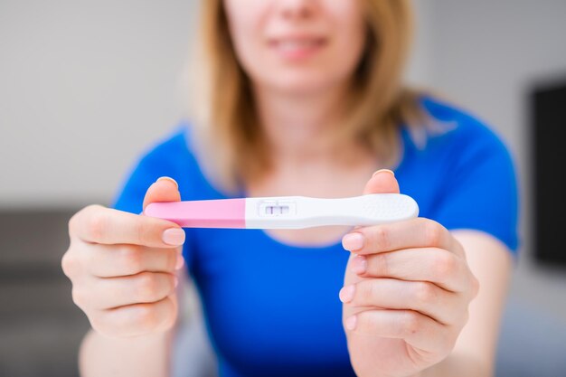 Blondynka uśmiechnięta kobieta trzyma pozytywny test ciążowy