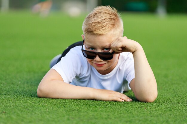 Blondynka w ciemnych okularach leży na boisku. Zdjęcie wysokiej jakości